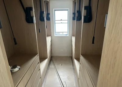 Walk-in robe with timber cabinetry and mirror panels during renovation at Palm Beach