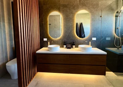 Luxury ensuite with dual vessel basins, LED-lit mirrors and timber slat feature wall at Palm Beach