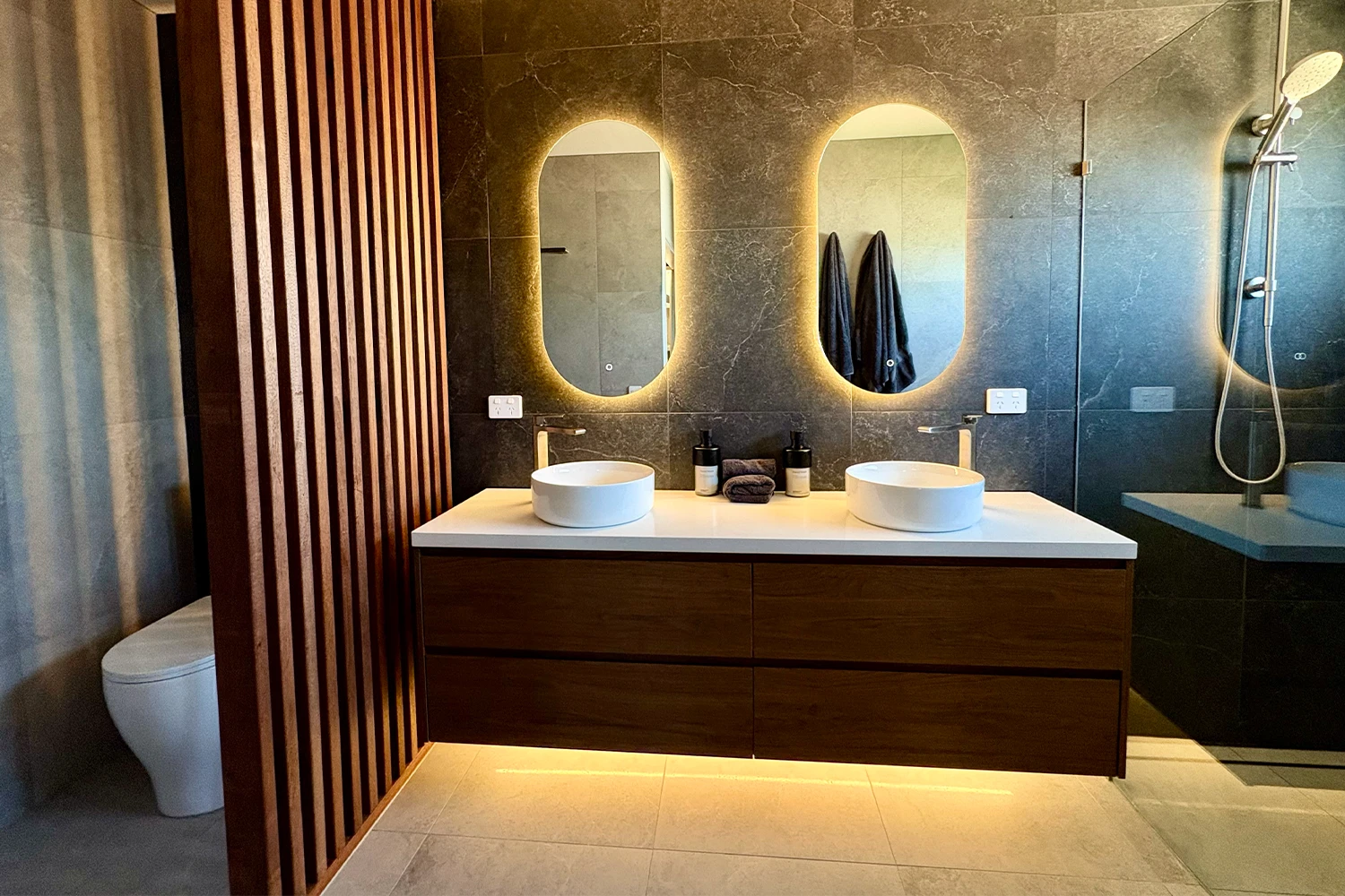 Luxury ensuite with dual vessel basins, LED-lit mirrors and timber slat feature wall at Palm Beach