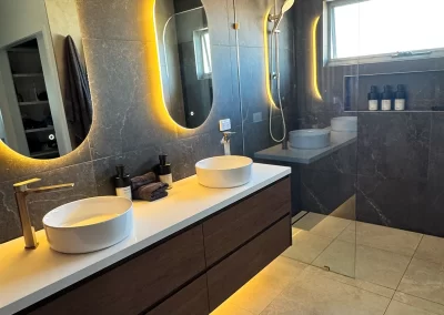 Finished ensuite with dual vessel basins, dark stone tiles and open walk-in shower at Palm Beach