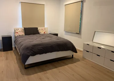 Renovated bedroom with light timber flooring, roller blinds and fresh paint at Main Beach