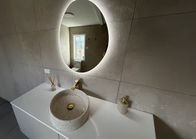 Finished vanity with stone vessel basin, LED round mirror and brass tapware at Main Beach