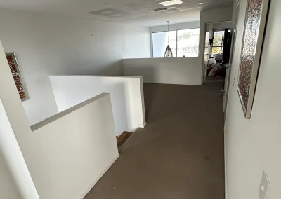Open landing area with half-wall and dated flooring before renovation at Palm Beach