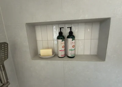 Tiled shower niche with white feature tiles and toiletries at Palm Beach