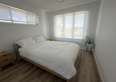 Renovated bedroom with timber bed frame, roller blinds and new flooring at Palm Beach, Gold Coast
