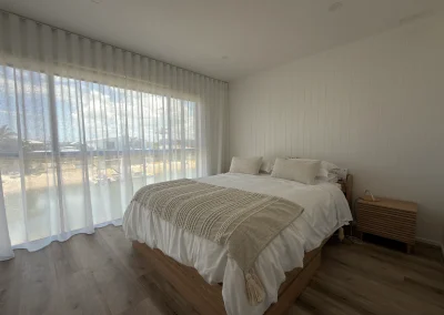 Renovated bedroom with timber flooring, sheer curtains and neutral tones at Palm Beach