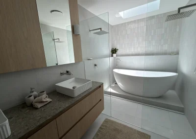 Finished ensuite with timber vanity, stone benchtop and freestanding bath at Palm Beach