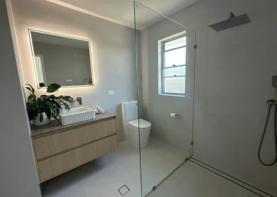 Completed bathroom with LED-lit mirror, floating vanity and frameless shower screen at Palm Beach