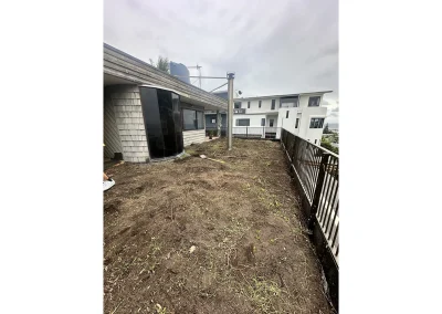 Cleared backyard with bare soil and weathered cladding before new deck installation in Currumbin