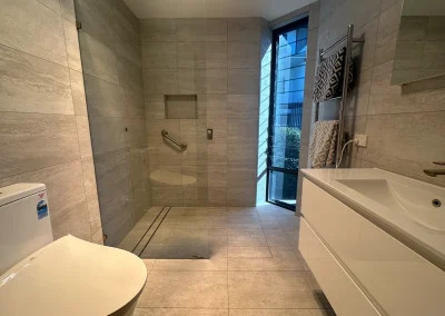 Completed bathroom with large format stone tiles, shower niche and wall-hung toilet in Currumbin